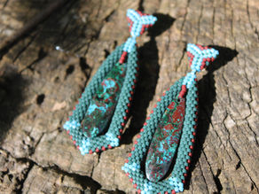 Two blue and red earrings with large stones in the center on a tree stump background.