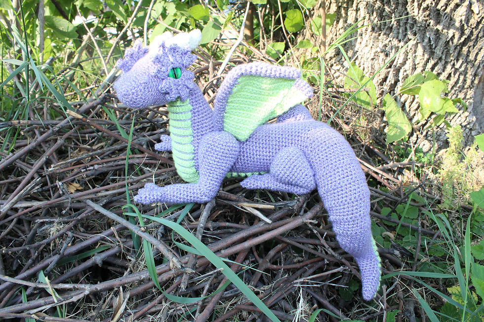 A purple crochet dragon sitting on a pile of sticks