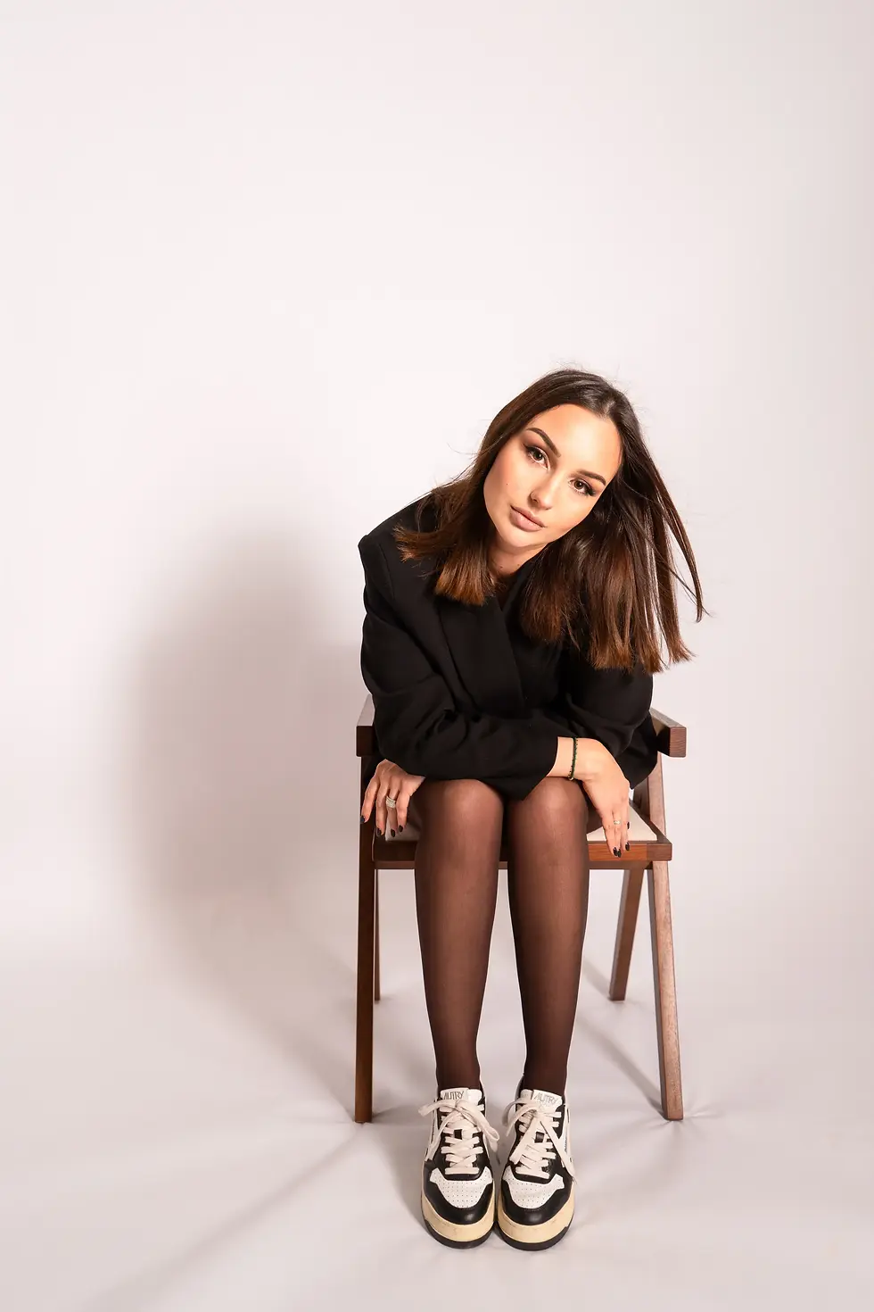 Jeune femme assise sur une chaise, regardant l'objectif, en studio, vêtements noirs.