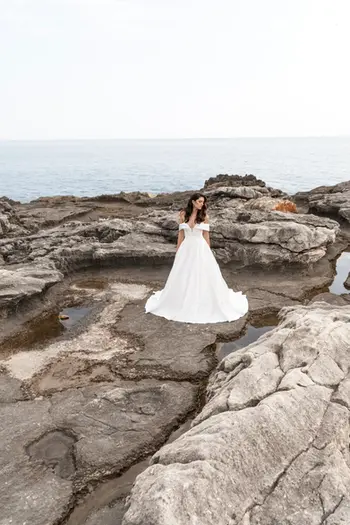 Mujer con vestido de novia en las rocas junto al mar.