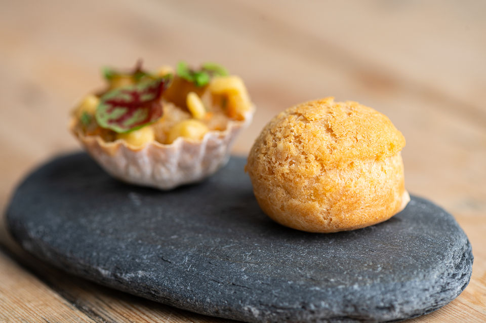 Close up of gougère and squash tartlet served on a flat stone.