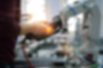 Close up of man's hand holding teach panel to control robotic arm which is integrated on