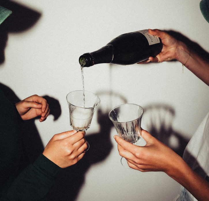 Twee personen schenken champagne in glazen in