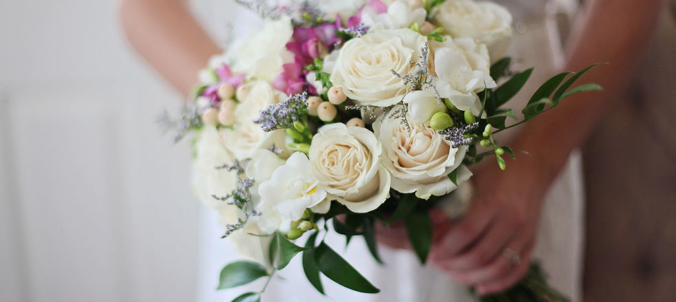 Hand tied bridal bouquet of all white and blush pink roses with minimal greenery, styled in a modern, elegant design.
