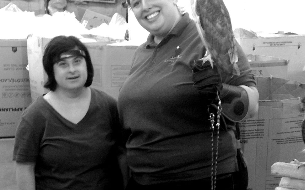 Smiling woman holding an owl with a New Avenues individual next to her.