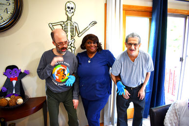Woman in blue scrubs next to two men.