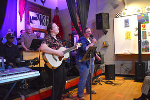 Two musicians performing, one playing guitar, another singing