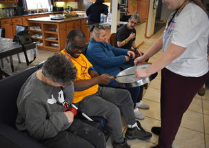 Person hands a tray to participants during a therapy session