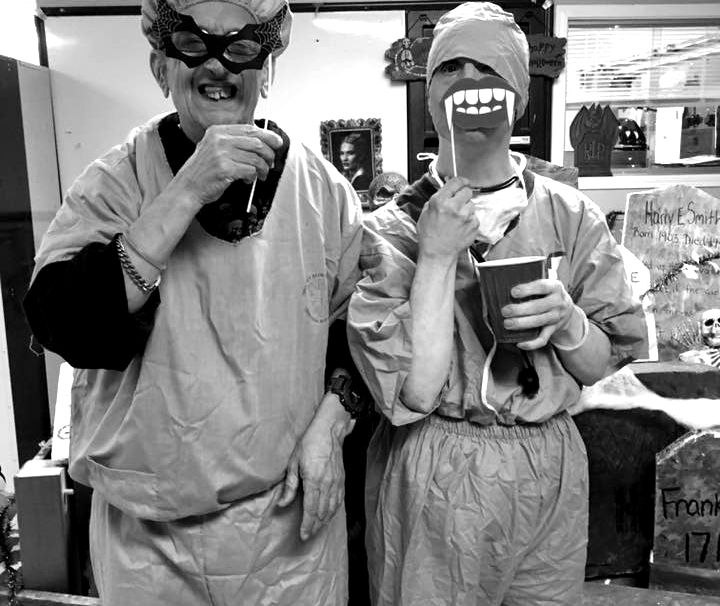 Two costumed figures, one masked, one with headwrap, drinking
