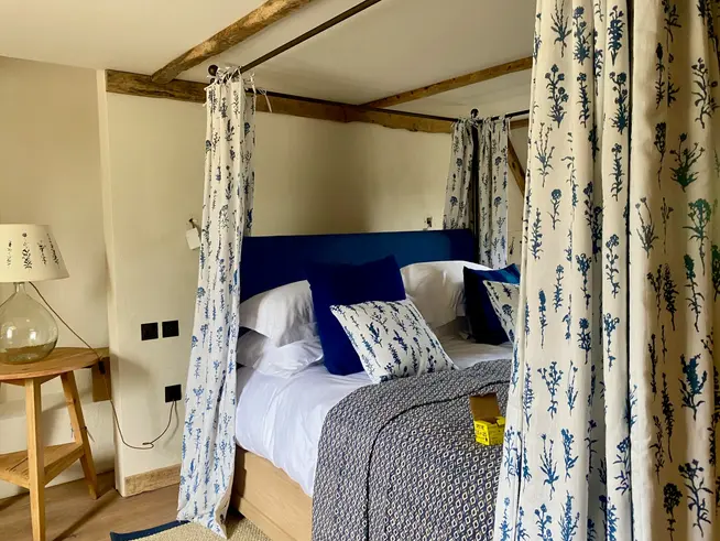 Floral blue and white four poster bed curtains on metal frame.