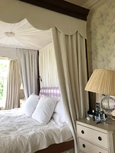 Cream four poster curtains, canopy and pelmet on wooden bed frame.