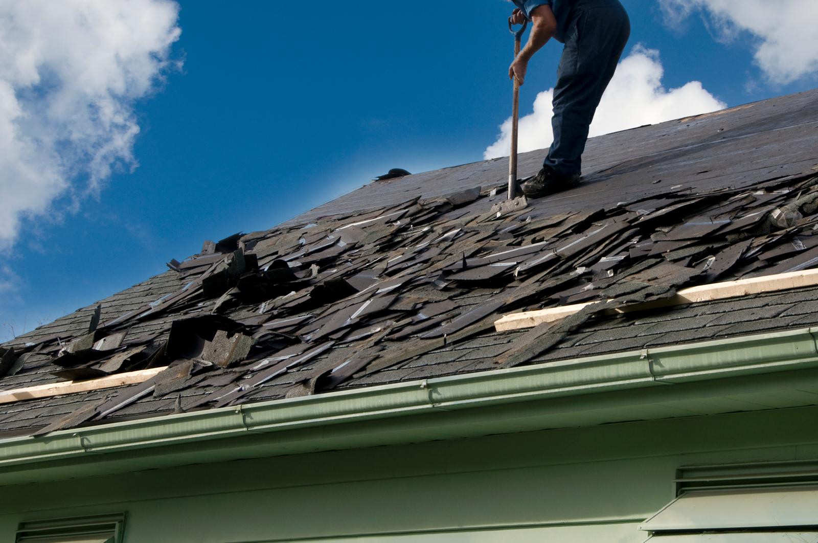 A worker removes old roofing materials.
