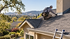 Shingle roof inspection with surrounding hills.