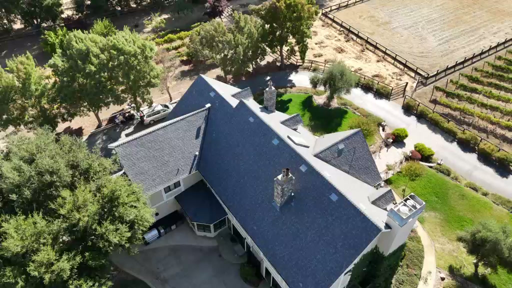Aerial views of a gray shingle roof, roof planes, chimneys and skylights