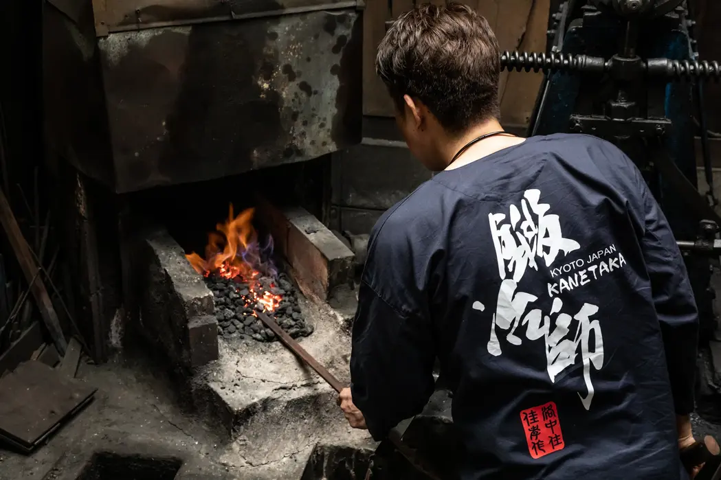 Master blacksmith in traditional indigo coat