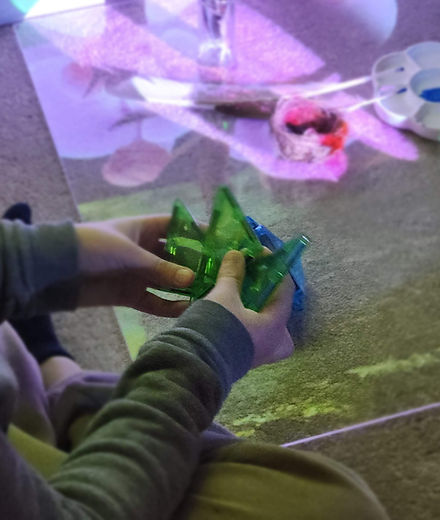 child's hand holding transparent magnet tiles