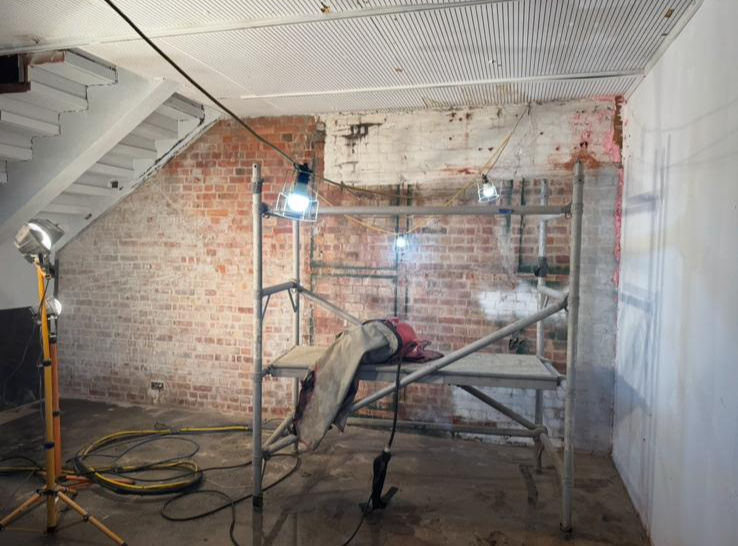 white wall under stairs with scaffolding and flood lights