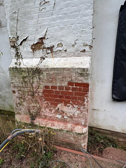 Peeling non-breathable paint coating on historic chimney stack brickwork before specialist paint removal and brick restoration in Hunsdon, Hertfordshire.