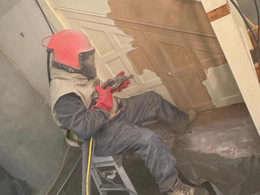 Removing paint by sandblasting from wooden staircase panels to expose natural timber