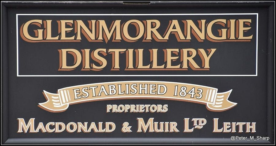 Vintage sign for Glenmorangie Distillery, Established 1843, with Macdonald & Muir Ltd Leith on a black background.