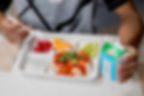 A child eats food from a school lunch tray