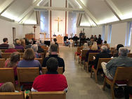 Congregation sitting rows of seats worshipping with bluegrass group playing at front of church