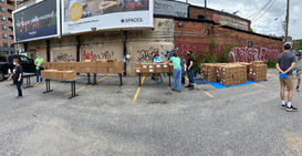 Group of adults setting up boxes of food to distribute at parking lot in the city