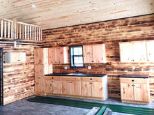 The kitchen of the Salmon Run cabin with light wood cabinets and partial view of the loft above.