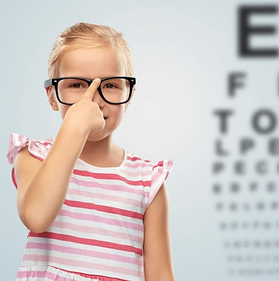 Lächelndes kleines Mädchen mit Brille über Sehtesttafel.jpg