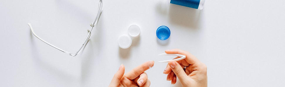 Nahaufnahme von Händen, die eine Kontaktlinse mit einer Pinzette handhaben.jpg