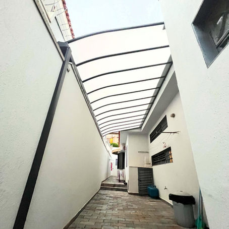 Cobertura em policarbonato sobre corredor lateral e garagem de residência, instalada pela Miraflex em Ribeirão Preto
