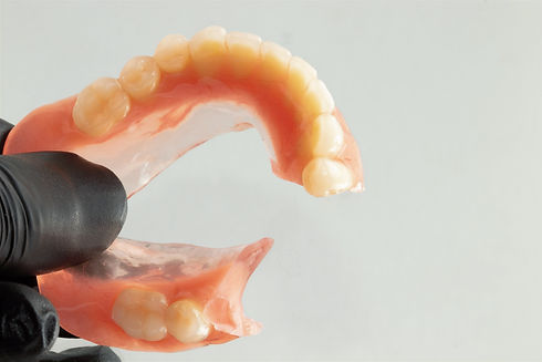 Woman holding a broken lower complete denture Selective focus_edited_edited.jpg