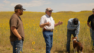 Rancher talking to a group of people in a pasture