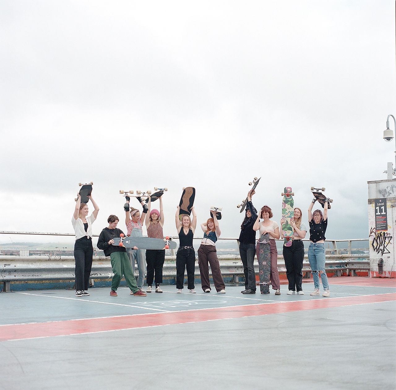 Girls with board in the air on multi-storey car park 