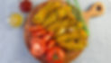 A wooden plate of fried food, tomatoes and greens with mustard and ketchup.