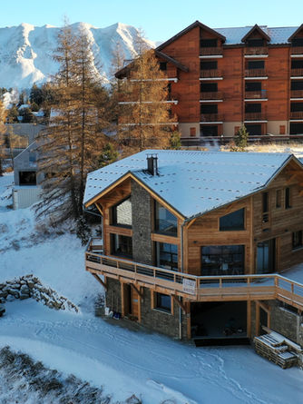 chalet enneigée vu du ciel, avec les montagnes en fond