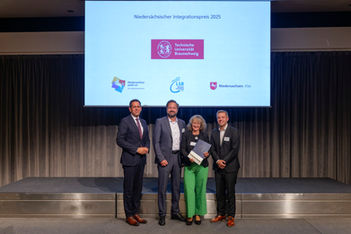 Vier Personen posieren im Rahmen des Niedersächsischen Integrationspreises 2025 mit Urkunden.