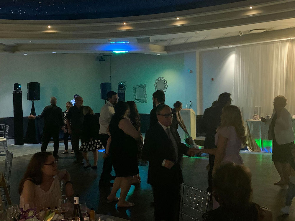 Guests dancing with DJ setup and lighting at an event.