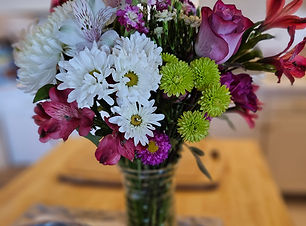 A mixed bouquet of fresh flowers in a glass vase sitting in a kitchen