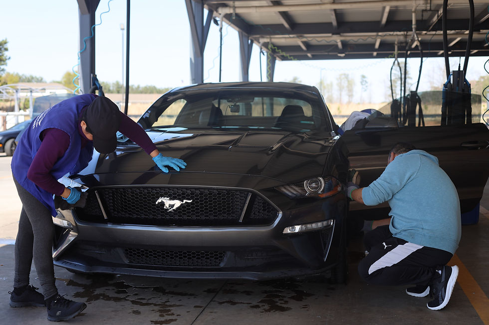 a woman cleaning a Mustang GTR and a man cleaning the wheels. 