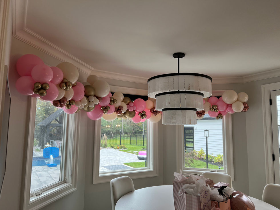 Pink fall-themed birthday balloon garland with baby pink, dusk cream, chrome gold, and rose gold balloons displayed across windows in Latham, NY.