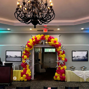 Large yellow and hot pink graduation balloon arch with silver starburst balloons at The Vista at Van Patten Golf Club in Clifton Park, NY.