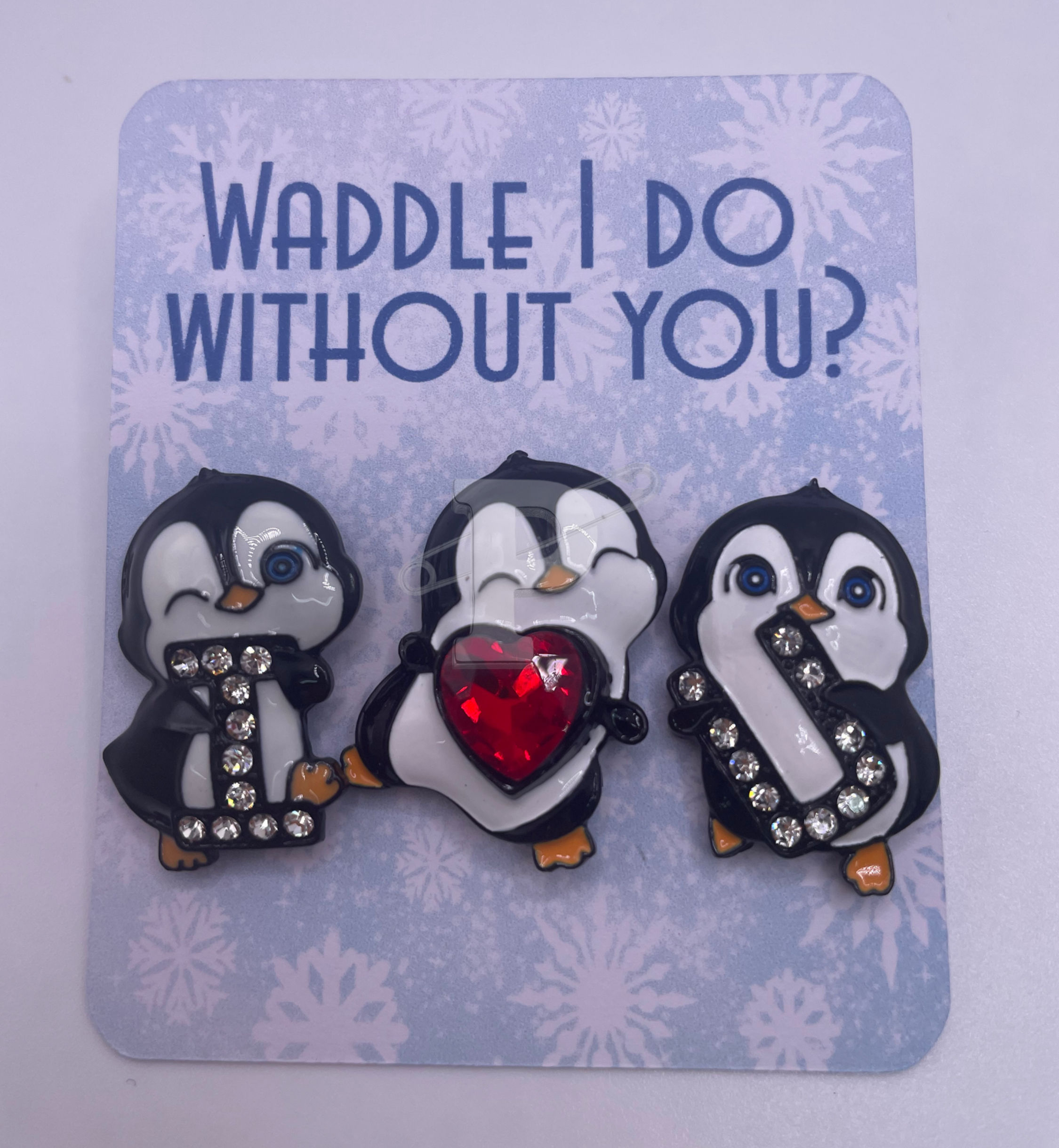 A flat card that reads Waddle I do without you with three penguin pins that spell out "I love (heart) you"