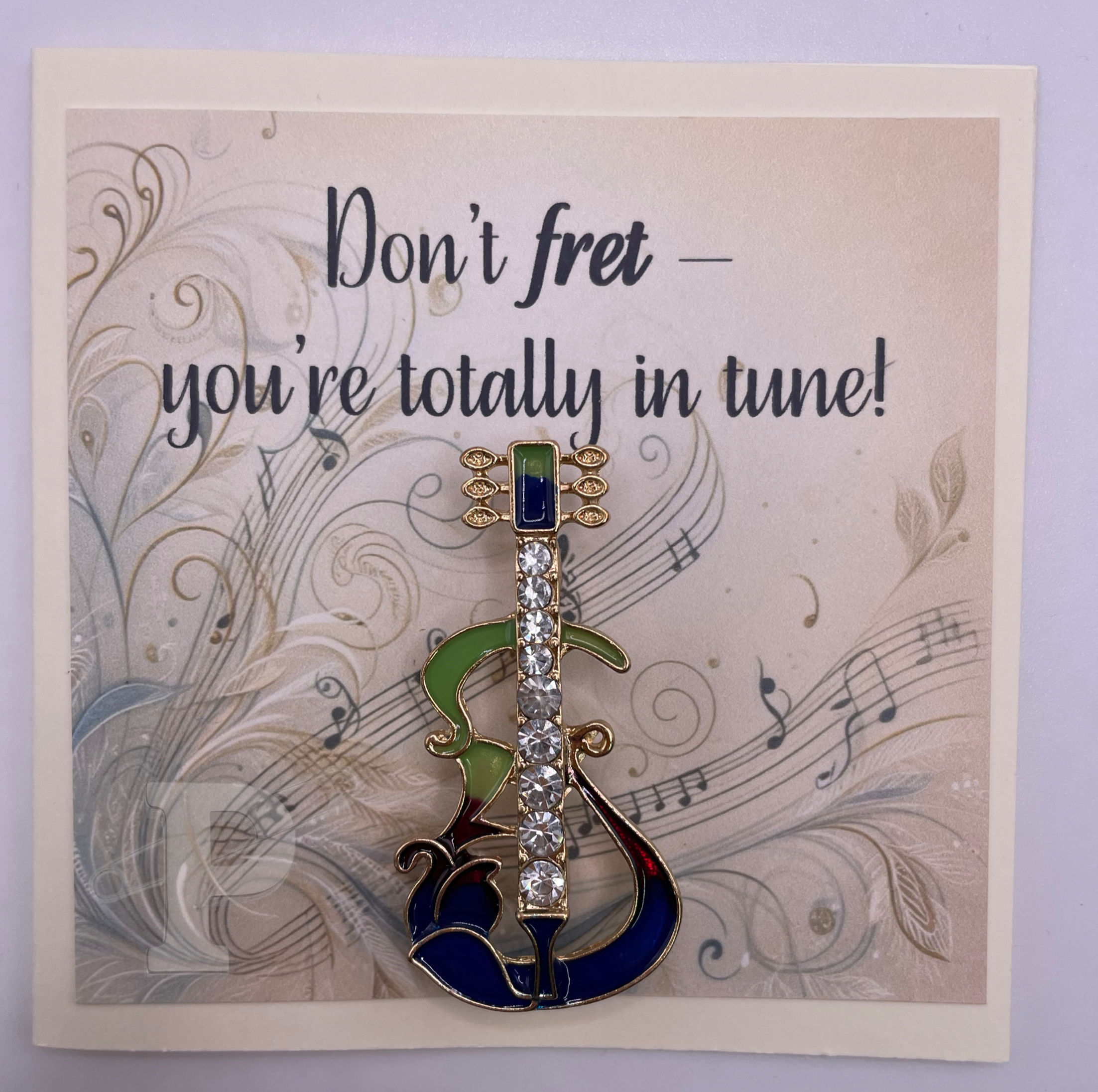 Greeting card that reads “Don’t fret — you’re totally in tune!” with colorful jeweled guitar brooch attached.