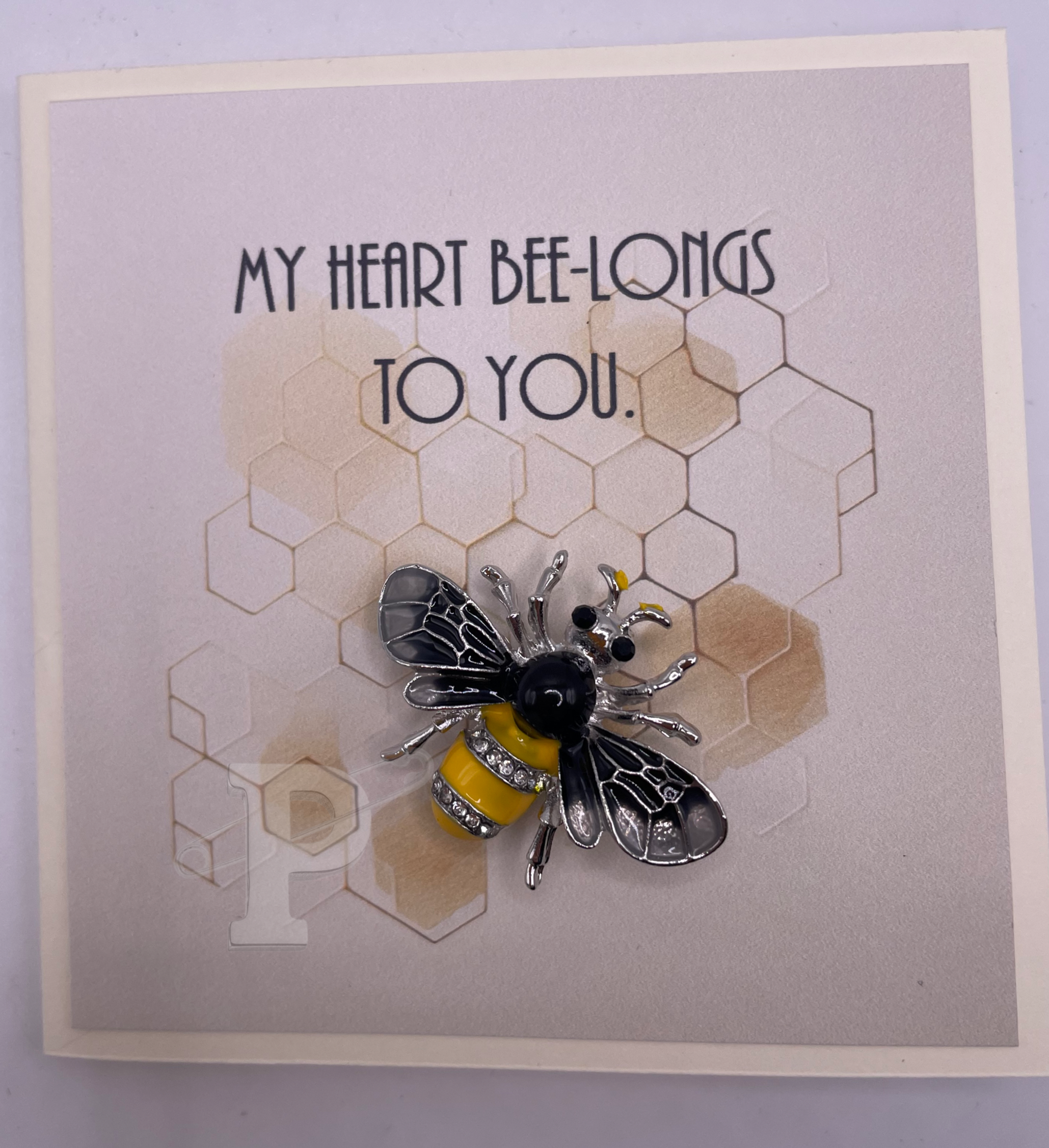 Mini greeting card that reads “My heart bee-longs to you” with a bee brooch attached