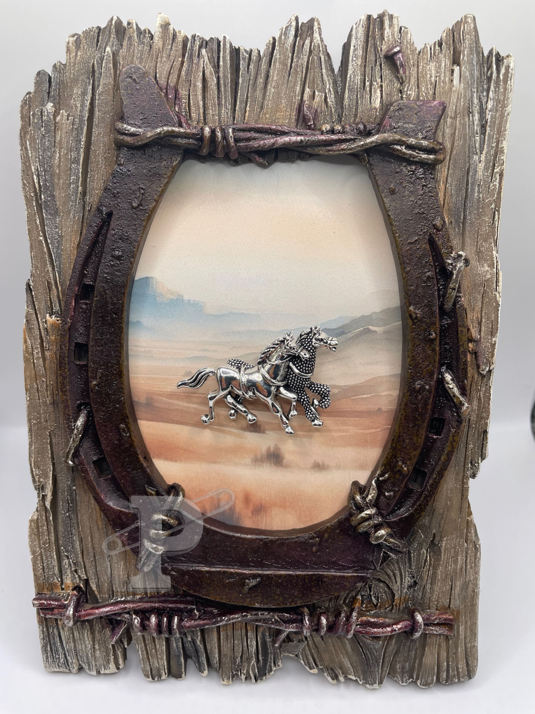 framed brooch art with silver running horses over soft western desert landscape in rustic horseshoe frame