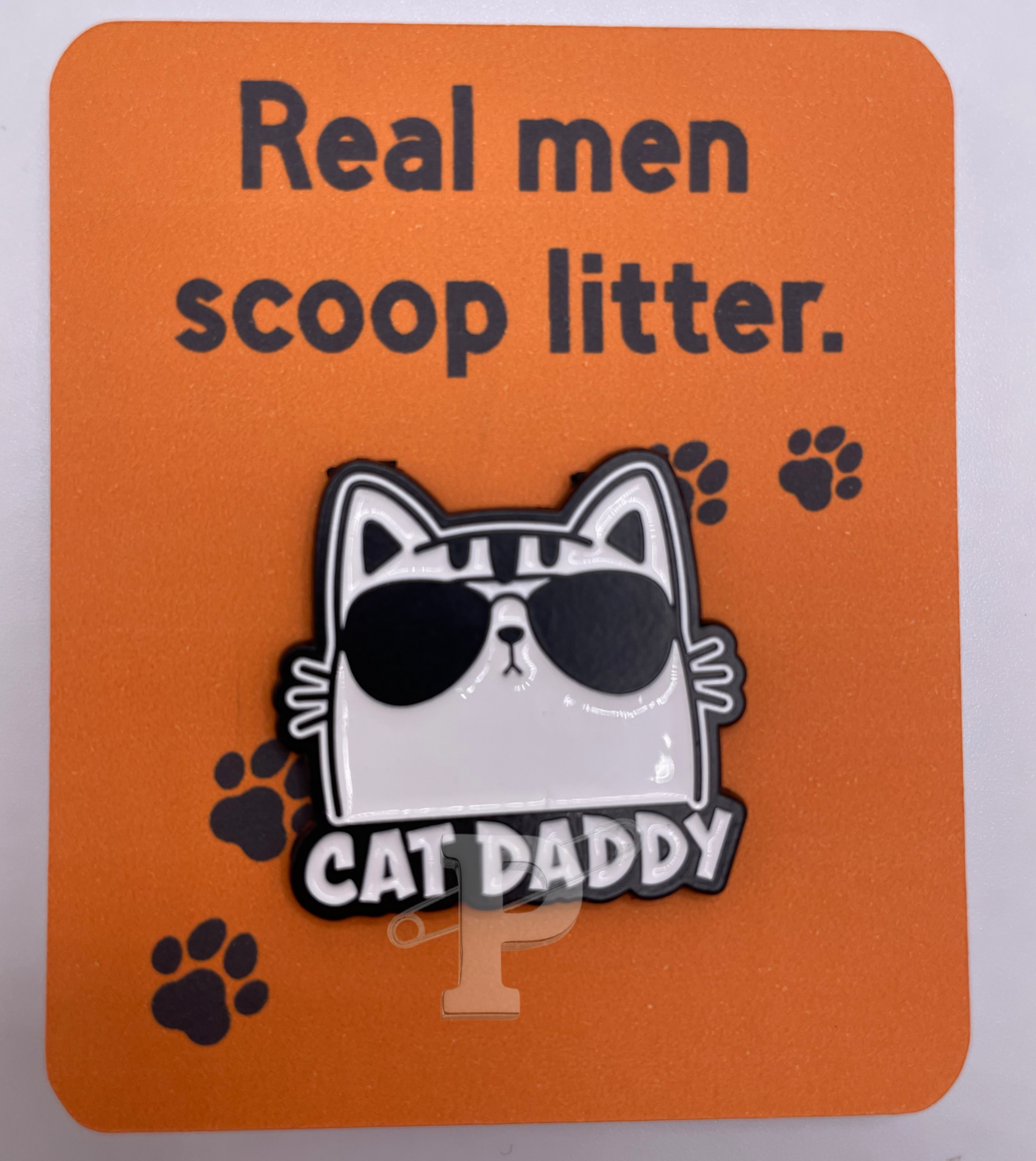 A flat card that reads "Real men scoop litter" with a "Cat daddy" pin attached.