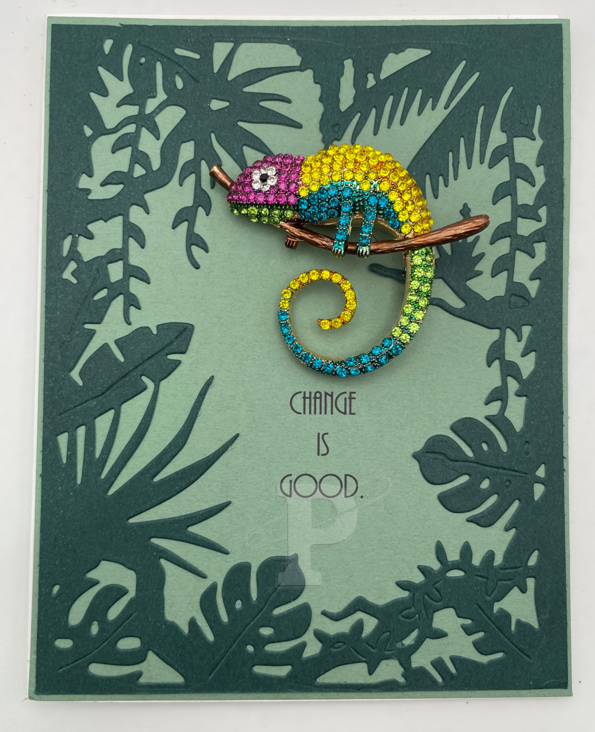 Vibrant card with rhinestone chameleon brooch in green jungle, symbolizing adaptability and transformation.