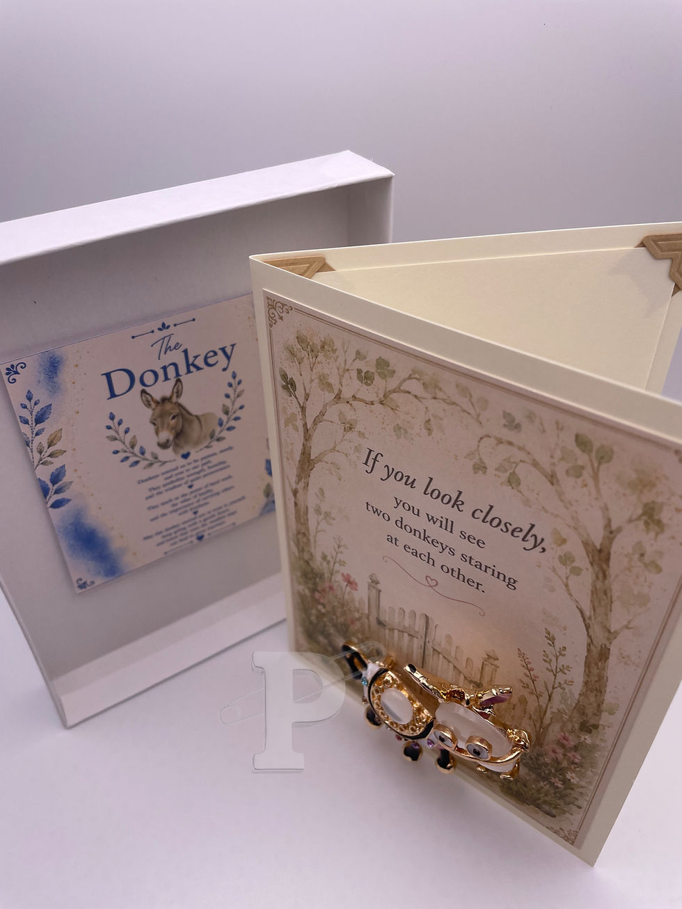 Gift-boxed donkey brooch greeting card displayed with the included Donkey Symbol Meaning Card inside the gift box.
