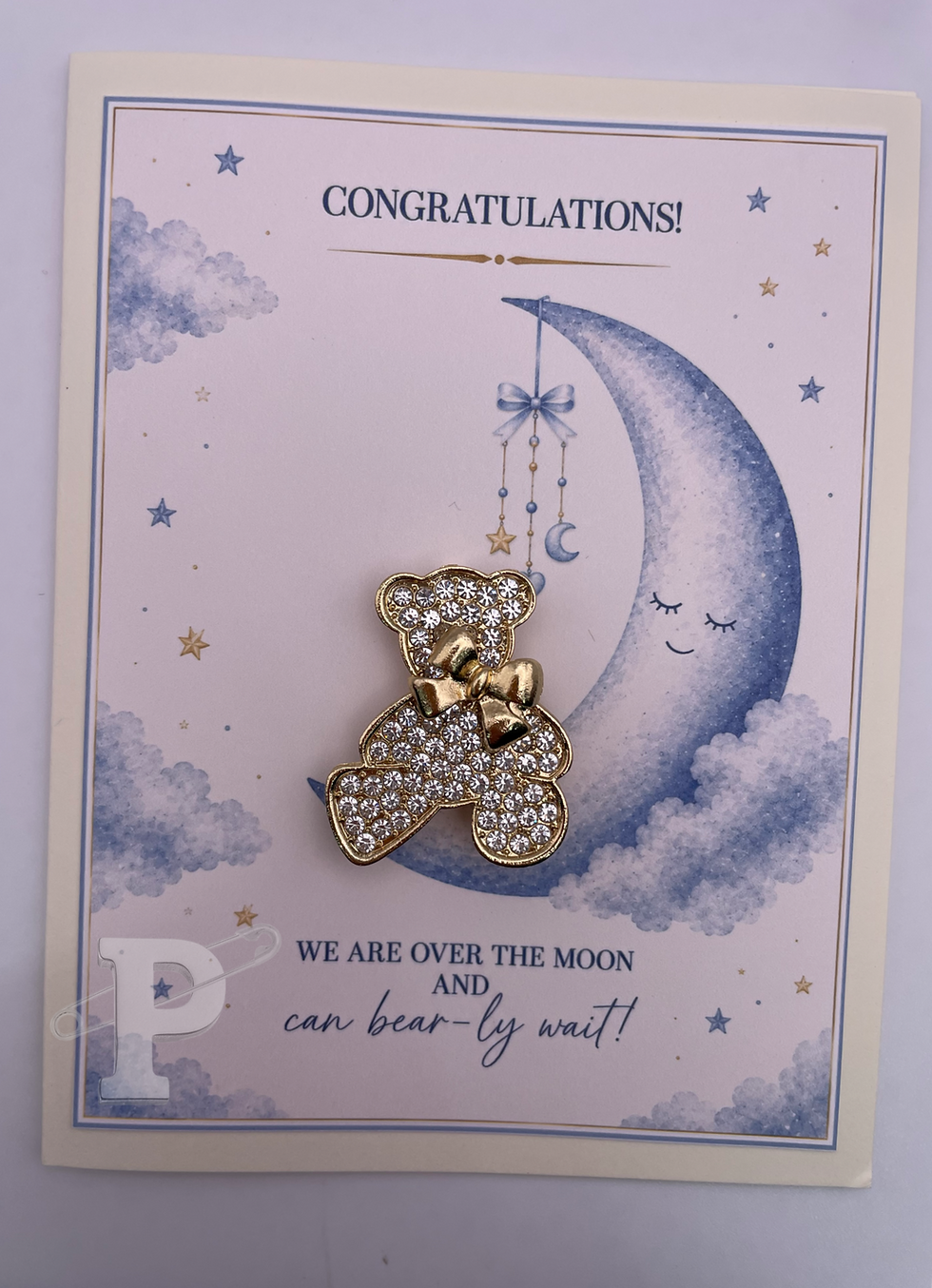 Baby congratulations card with teddy bear brooch and moon.